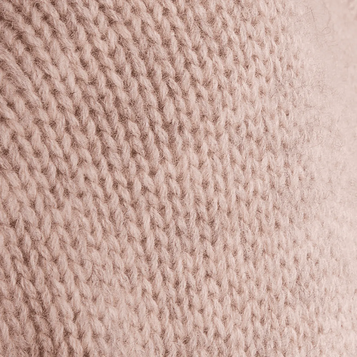 Primo piano di una maglia di cashmere rosa cipria, punto spesso e soffice.