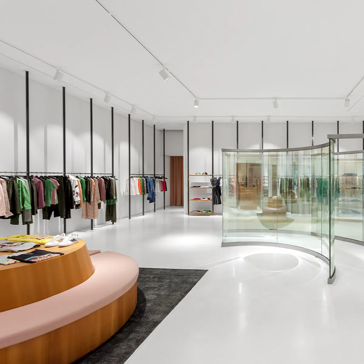White room with black uprights and a curved glass display case at the Avenue Louise boutique.