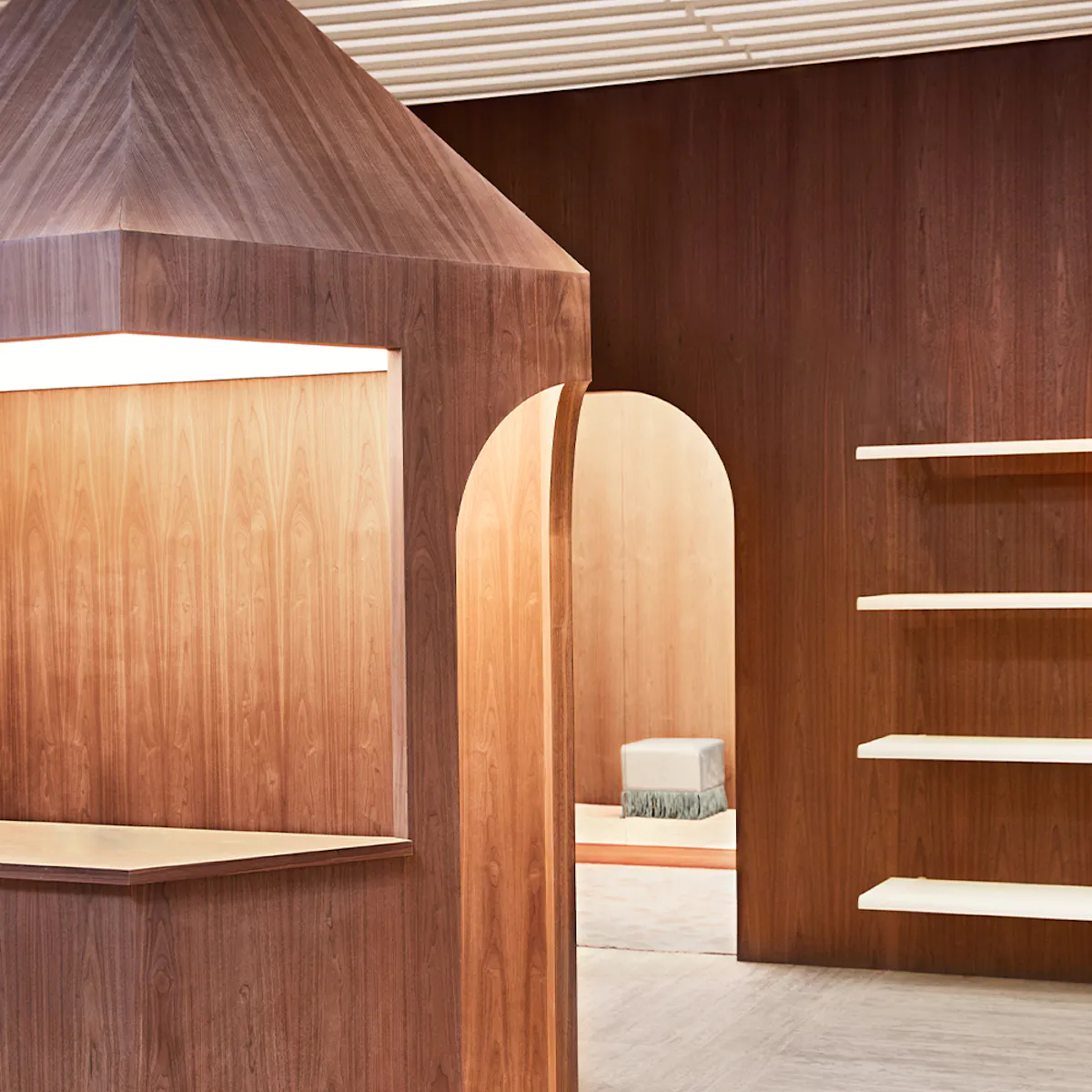 Interno di una boutique Zadig&Voltaire con calde boiserie e scaffali in legno ad arco.