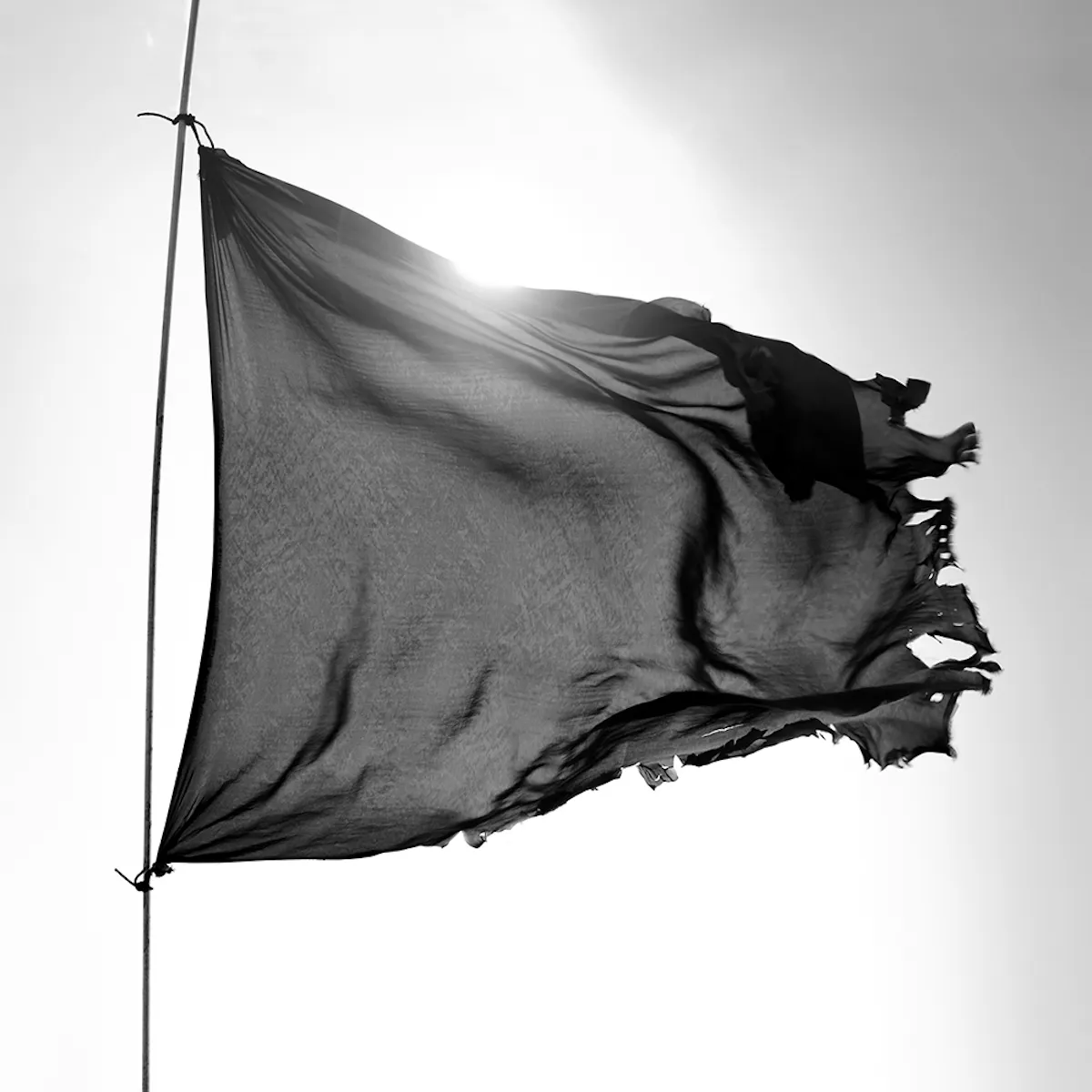 Bandiera nera che sventola al vento su un cielo bianco, in bianco e nero.