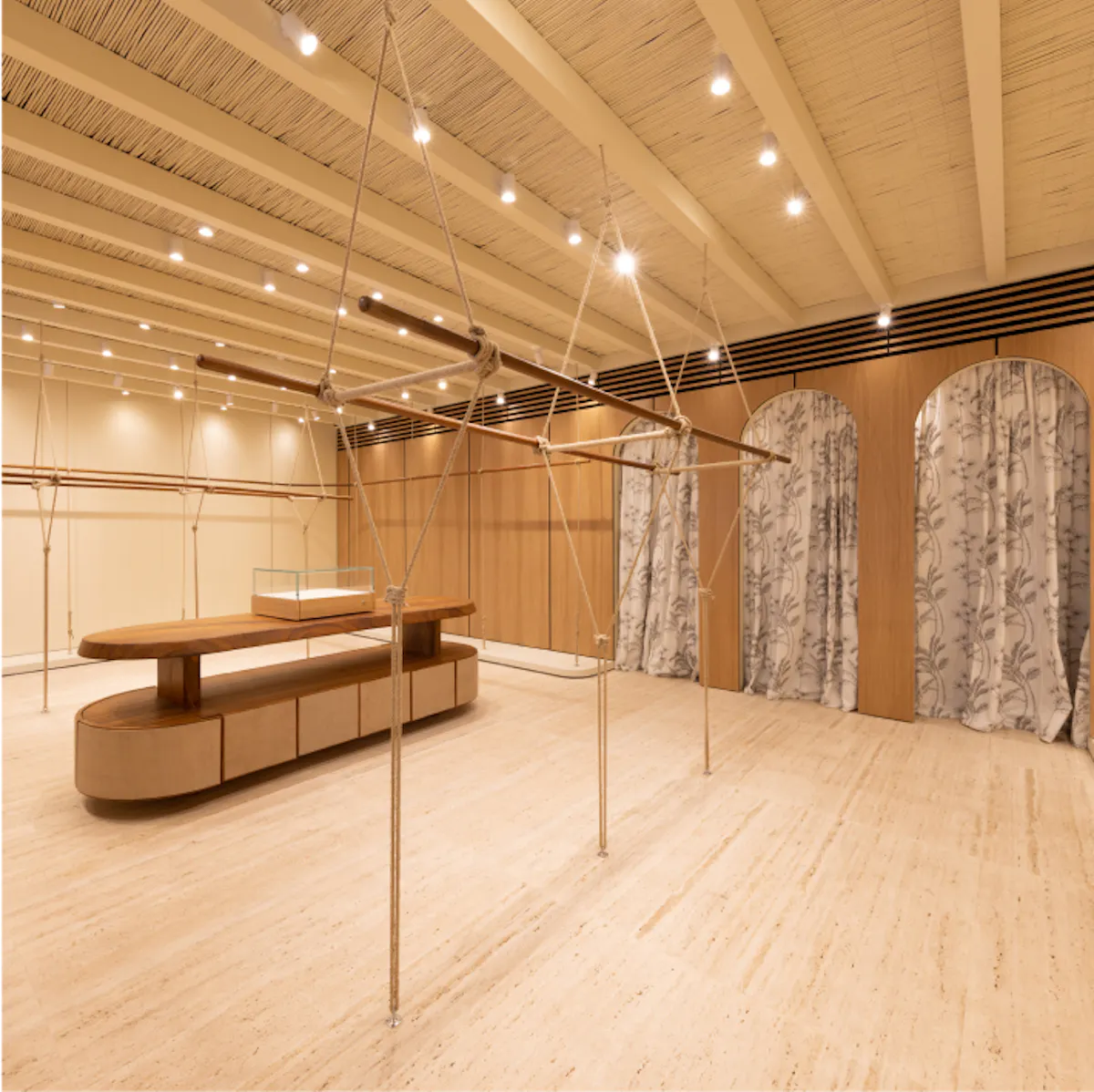 Intérieur clair d’une boutique Zadig&Voltaire : plafond de bois, structure en cordes, vitrine centrale et cabines à rideaux